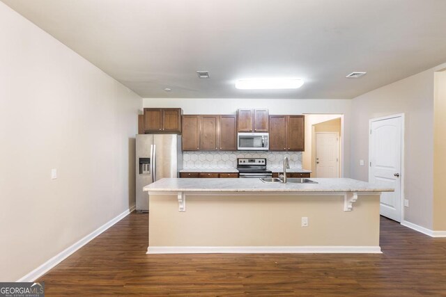 208 Flowing Meadows Dr, Kathleen, GA 31047 - kitchen featuring appliances with stainless steel finishes, backsplash, dark wood finished floors, and a center island with sink