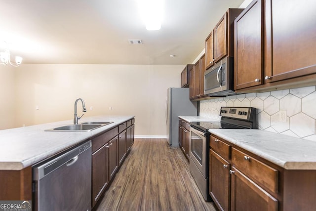 208 Flowing Meadows Dr, Kathleen, GA 31047 - kitchen with stainless steel appliances, dark wood-style flooring, decorative backsplash, light countertops, and an island with sink
