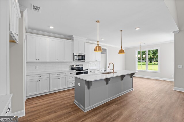 9 Honeysuckle Dr, Claxton, GA 30417 - kitchen featuring appliances with stainless steel finishes, crown molding, white cabinets, backsplash, and wood finished floors