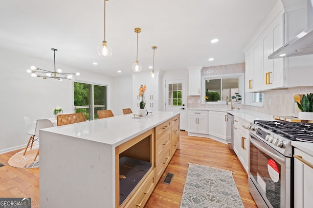 3222 Edgemont Way, Decatur, GA 30032 - kitchen with wall chimney exhaust hood, stainless steel appliances, tasteful backsplash, a center island, and light wood-type flooring