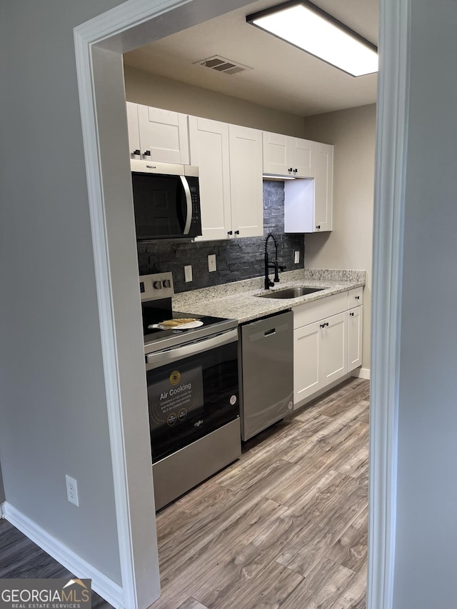 105 Ridgefield Dr, Lagrange, GA 30241 - kitchen with stainless steel appliances, decorative backsplash, light wood finished floors, and white cabinetry