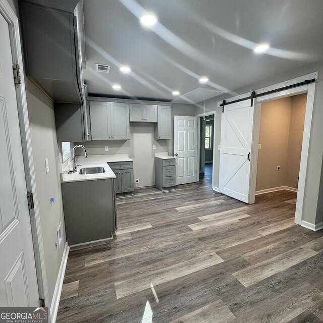 1425 Walls Ln, Macon, GA 31211 - kitchen with a barn door, gray cabinets, wood finished floors, recessed lighting, and light countertops