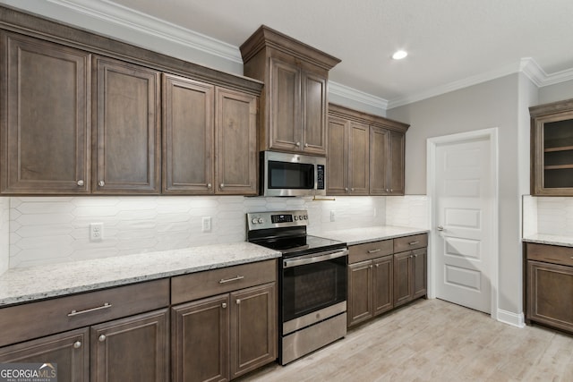 183 Ryan Nicholas Dr, Kingsland, GA 31548 - kitchen with stainless steel appliances, tasteful backsplash, light wood-style floors, light stone counters, and crown molding
