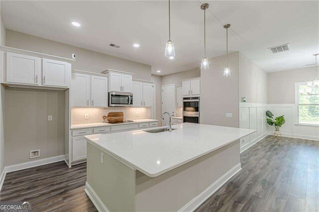 150 Whitworth Dr, Locust Grove, GA 30248 - kitchen featuring appliances with stainless steel finishes, dark wood finished floors, a spacious island, white cabinetry, and decorative backsplash