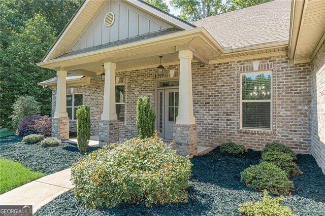150 Whitworth Dr, Locust Grove, GA 30248 - entrance to property with board and batten siding, brick siding, a shingled roof, and a porch