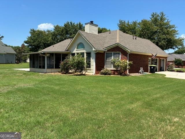 9361 Arbor Glenn Ct, Jonesboro, GA 30263 - single story home featuring a front yard, a sunroom, a chimney, a garage, and driveway