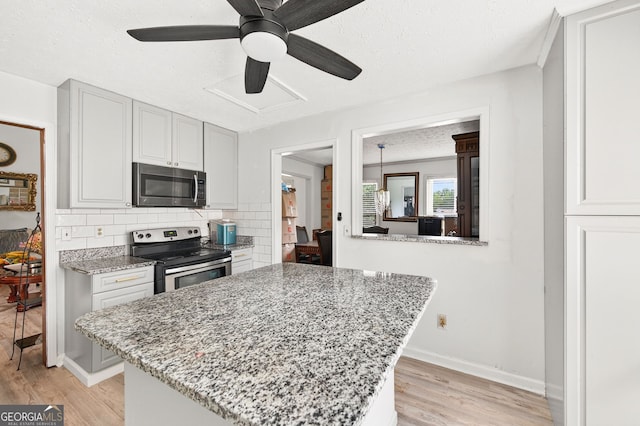936 Tyrell Dr, Austell, GA 30106 - kitchen with appliances with stainless steel finishes, light wood finished floors, backsplash, a ceiling fan, and light stone countertops
