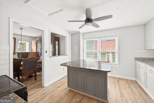 936 Tyrell Dr, Austell, GA 30106 - kitchen featuring a textured ceiling, black range with electric stovetop, light wood-style floors, dark stone counters, and a ceiling fan