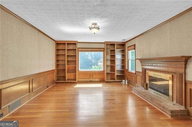 2830 Scottish Mill Way, Marietta, GA 30068 - unfurnished living room with ornamental molding, hardwood / wood-style flooring, a brick fireplace, built in features, and a textured ceiling