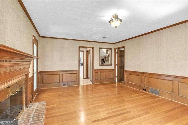 2830 Scottish Mill Way, Marietta, GA 30068 - unfurnished living room with a fireplace, light wood finished floors, ornamental molding, wainscoting, and a textured ceiling