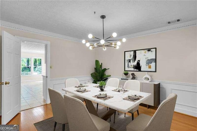 2830 Scottish Mill Way, Marietta, GA 30068 - dining room featuring crown molding, a chandelier, light wood finished floors, a textured ceiling, and a wainscoted wall