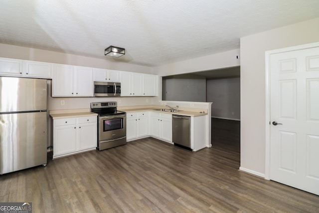 183 Arrowhead Dr, Dallas, GA 30132 - kitchen with appliances with stainless steel finishes, light countertops, dark wood finished floors, white cabinets, and a peninsula