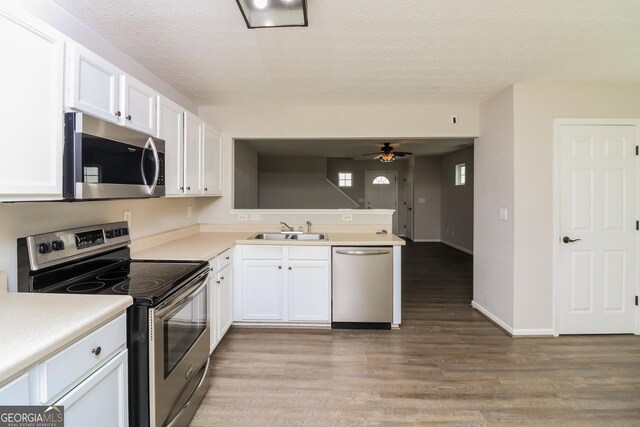 183 Arrowhead Dr, Dallas, GA 30132 - kitchen with stainless steel appliances, light wood-type flooring, a peninsula, white cabinetry, and a ceiling fan