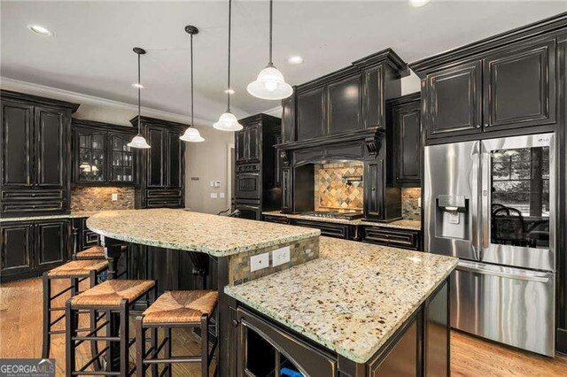 908 Basingstoke Ct, Suwanee, GA 30024 - kitchen featuring stainless steel appliances, a center island, dark cabinetry, decorative backsplash, and light wood-style flooring