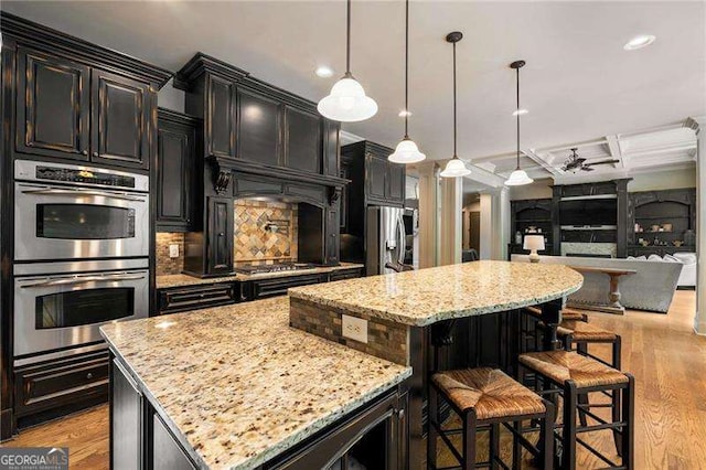 908 Basingstoke Ct, Suwanee, GA 30024 - kitchen featuring appliances with stainless steel finishes, a kitchen island, open floor plan, light stone countertops, and light wood-style floors