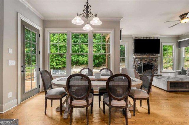 908 Basingstoke Ct, Suwanee, GA 30024 - dining room with a stone fireplace, crown molding, light wood finished floors, a chandelier, and ceiling fan