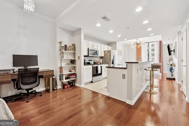 3040 Peachtree Rd NW Unit 702, Atlanta, GA 30305 - kitchen featuring stainless steel appliances, a chandelier, light wood-style floors, a center island with sink, and recessed lighting