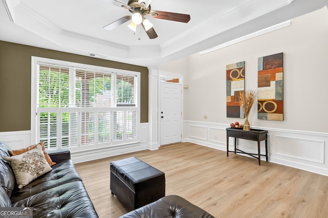 1065 Bookhout Dr, Cumming, GA 30041 - living room featuring a raised ceiling, light wood-style flooring, crown molding, a wainscoted wall, and a ceiling fan