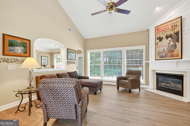 1065 Bookhout Dr, Cumming, GA 30041 - living room featuring ceiling fan, light wood-style flooring, high vaulted ceiling, and a glass covered fireplace