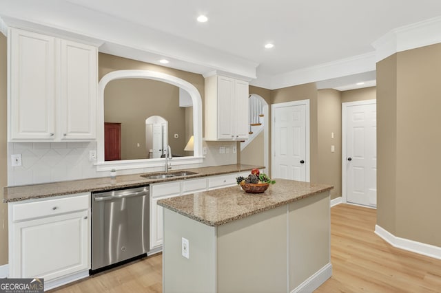1065 Bookhout Dr, Cumming, GA 30041 - kitchen featuring stainless steel dishwasher, arched walkways, white cabinets, a kitchen island, and light wood-style floors
