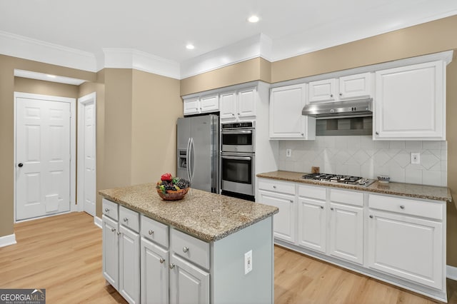 1065 Bookhout Dr, Cumming, GA 30041 - kitchen with stainless steel appliances, light wood-style flooring, a kitchen island, backsplash, and crown molding