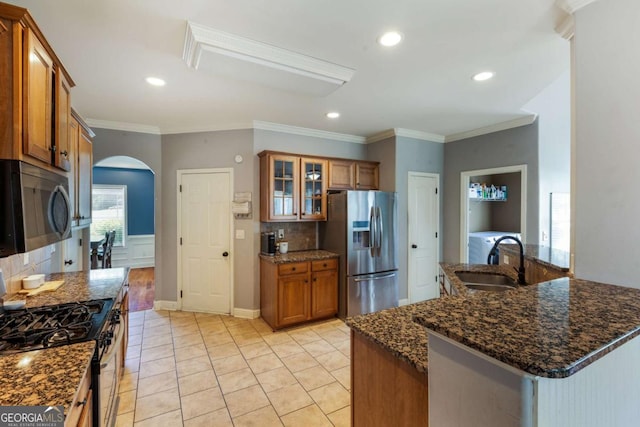 168 Gatlin Ridge Run, Dallas, GA 30157 - kitchen featuring stainless steel appliances, brown cabinets, backsplash, arched walkways, and dark stone countertops