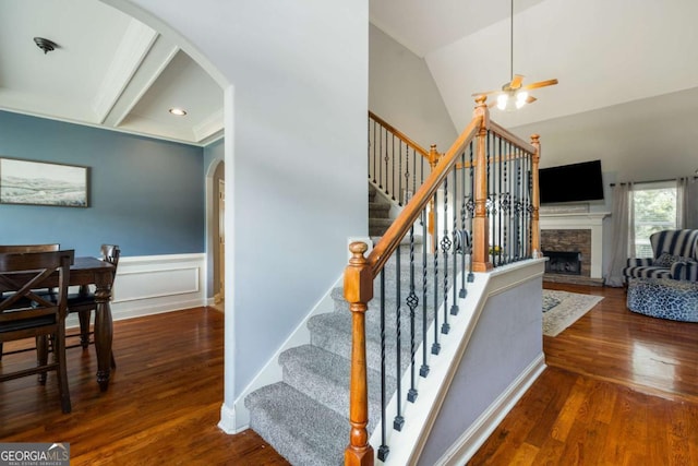 168 Gatlin Ridge Run, Dallas, GA 30157 - stairs featuring arched walkways, wood finished floors, a stone fireplace, ceiling fan, and a wainscoted wall