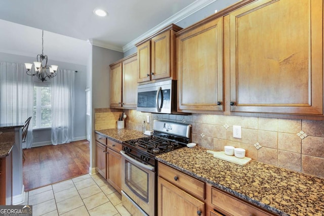 168 Gatlin Ridge Run, Dallas, GA 30157 - kitchen with appliances with stainless steel finishes, a chandelier, dark stone countertops, tasteful backsplash, and ornamental molding