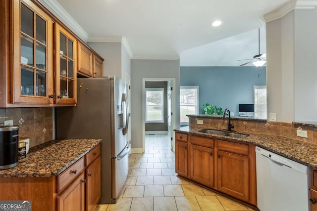 168 Gatlin Ridge Run, Dallas, GA 30157 - kitchen featuring white dishwasher, brown cabinetry, a ceiling fan, decorative backsplash, and dark stone countertops