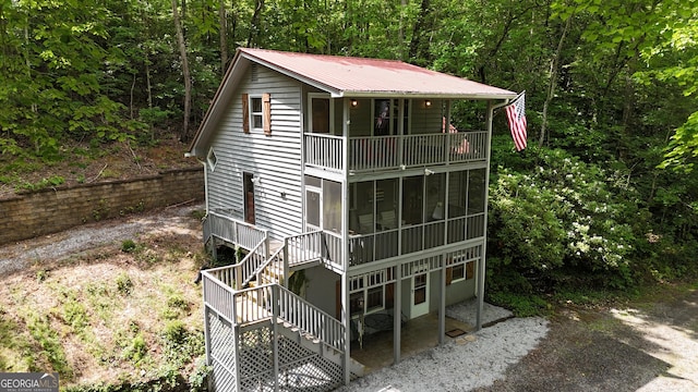 132 Wild Horse Cove Cir, Cleveland, GA 30528 - view of front of house featuring a balcony, stairway, a metal roof, a wooded view, and a sunroom