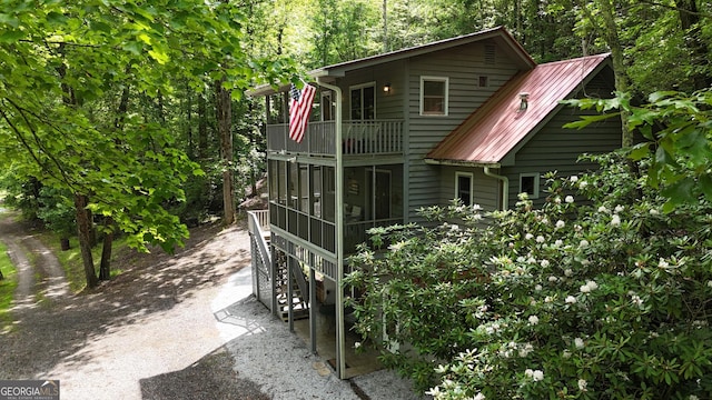 132 Wild Horse Cove Cir, Cleveland, GA 30528 - back of property featuring a balcony, dirt driveway, a sunroom, and a metal roof