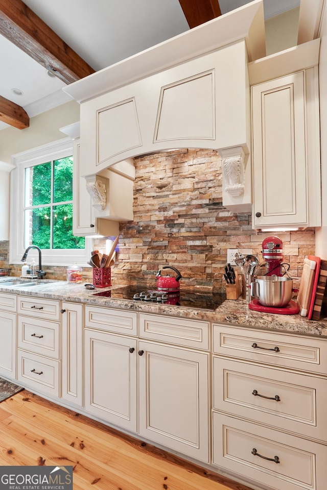 5130 Pratt St SW, Covington, GA 30014 - kitchen featuring beam ceiling, tasteful backsplash, light wood finished floors, black electric stovetop, and light stone countertops