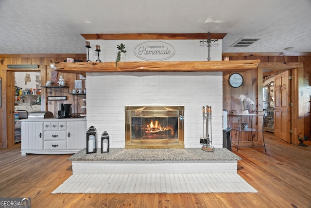 2296 Athens Rd, Royston, GA 30662 - detailed view of wooden walls, a textured ceiling, a brick fireplace, and wood finished floors