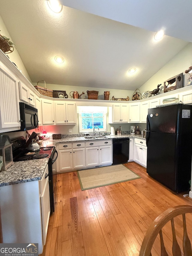 105 Evergreen Rd, Hiawassee, GA 30546 - kitchen featuring black appliances, lofted ceiling, white cabinetry, light wood-type flooring, and light stone counters