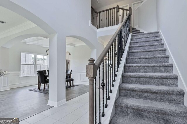 358 Brookhaven Loop NE, Ludowici, GA 31316 - stairs featuring arched walkways, crown molding, a decorative wall, wainscoting, and wood finished floors