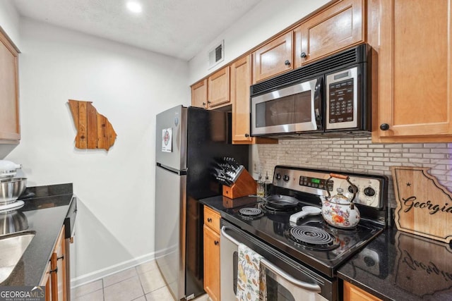 3115 Seven Pines Ct Unit 308, Atlanta, GA 30339 - kitchen featuring appliances with stainless steel finishes, light tile patterned floors, backsplash, and dark stone counters