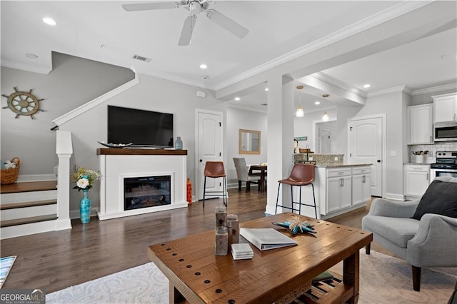 509 Mariners Cir, Saint Simons, GA 31522 - living area featuring dark wood-type flooring, recessed lighting, ceiling fan, ornamental molding, and stairs
