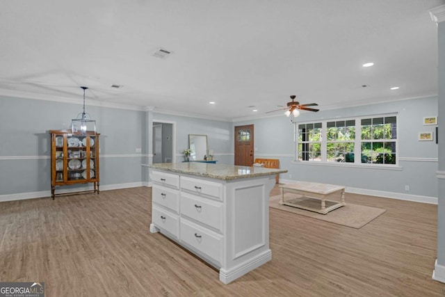 1207 College Ave, Blackshear, GA 31516 - kitchen with ceiling fan, light wood-style floors, crown molding, white cabinetry, and a kitchen island