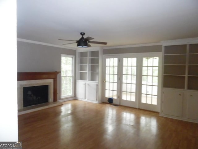 1205 Pebble Bend Dr, Grayson, GA 30017 - unfurnished living room featuring a ceiling fan, wood finished floors, a fireplace with raised hearth, crown molding, and built in shelves