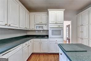 2324 Blackberry Ct, Snellville, GA 30078 - kitchen with white appliances, dark countertops, white cabinets, and light wood-style floors
