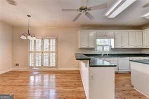 2324 Blackberry Ct, Snellville, GA 30078 - kitchen featuring white cabinets, a peninsula, dark countertops, wood finished floors, and a chandelier