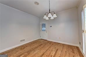 2324 Blackberry Ct, Snellville, GA 30078 - unfurnished dining area with a chandelier, wood finished floors, and ornamental molding
