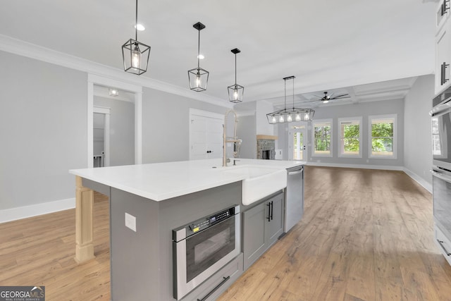 153 Alaina Rd, Holly Springs, GA 30115 - kitchen featuring stainless steel dishwasher, gray cabinets, open floor plan, a ceiling fan, and light wood finished floors