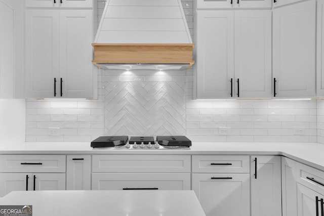 153 Alaina Rd, Holly Springs, GA 30115 - kitchen with range hood, backsplash, light countertops, gas cooktop, and white cabinets