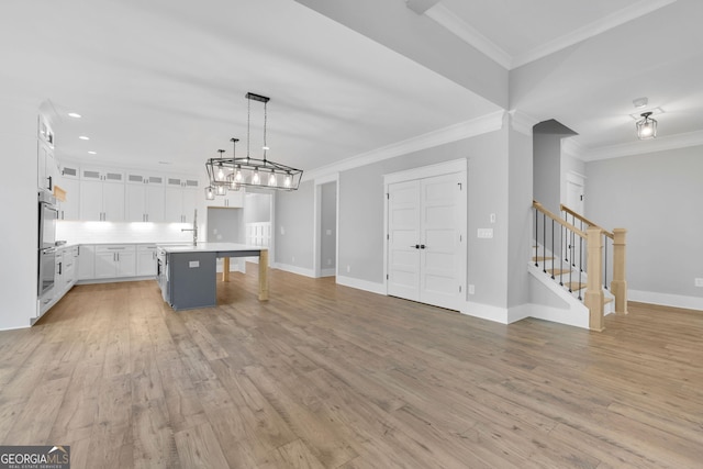 153 Alaina Rd, Holly Springs, GA 30115 - kitchen with double oven, white cabinets, crown molding, open floor plan, and light wood finished floors