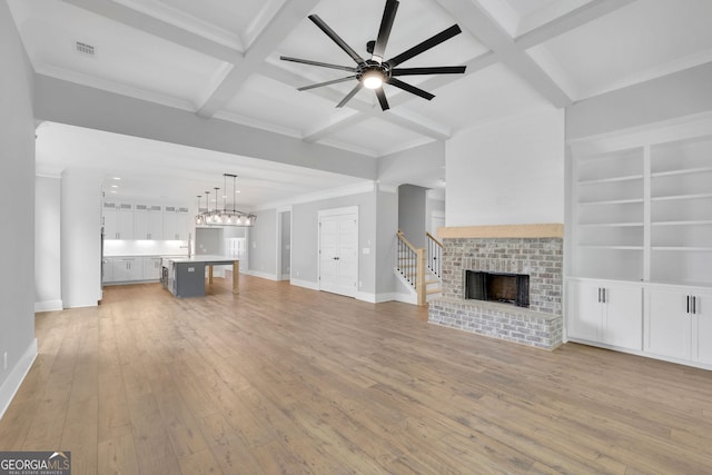 153 Alaina Rd, Holly Springs, GA 30115 - unfurnished living room featuring coffered ceiling, light wood-style flooring, a brick fireplace, a ceiling fan, and beam ceiling