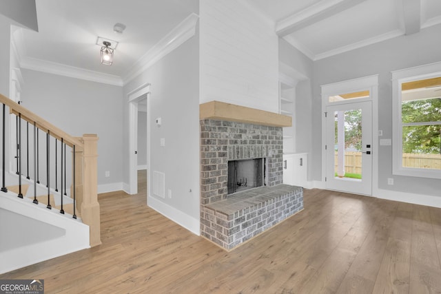 153 Alaina Rd, Holly Springs, GA 30115 - unfurnished living room with wood-type flooring, crown molding, stairs, a brick fireplace, and beamed ceiling