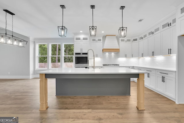 153 Alaina Rd, Holly Springs, GA 30115 - kitchen with custom exhaust hood, light countertops, tasteful backsplash, an island with sink, and recessed lighting