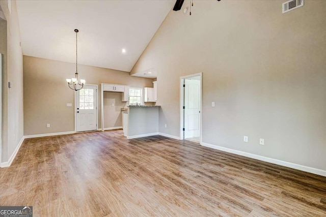 211 Loftis Rd, Temple, GA 30179 - unfurnished living room with ceiling fan, a chandelier, high vaulted ceiling, and light wood-style flooring