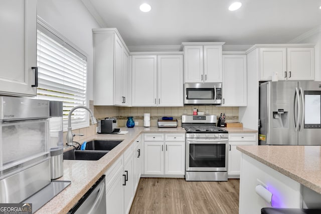 425 Eldridge Dr, Suwanee, GA 30024 - kitchen featuring appliances with stainless steel finishes, white cabinets, tasteful backsplash, light wood-type flooring, and ornamental molding